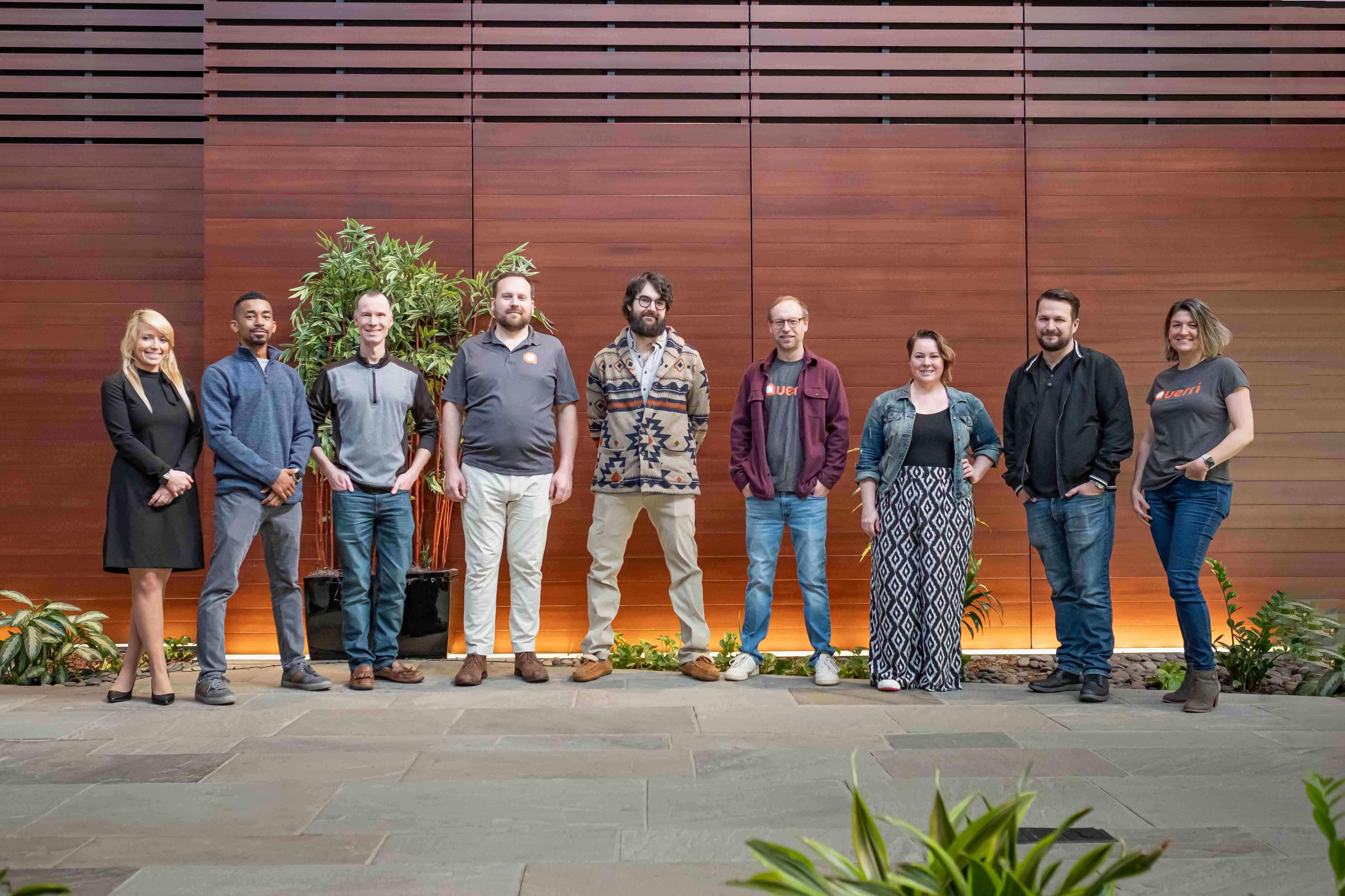 Diverse team of Querri employees standing together in modern office setting
